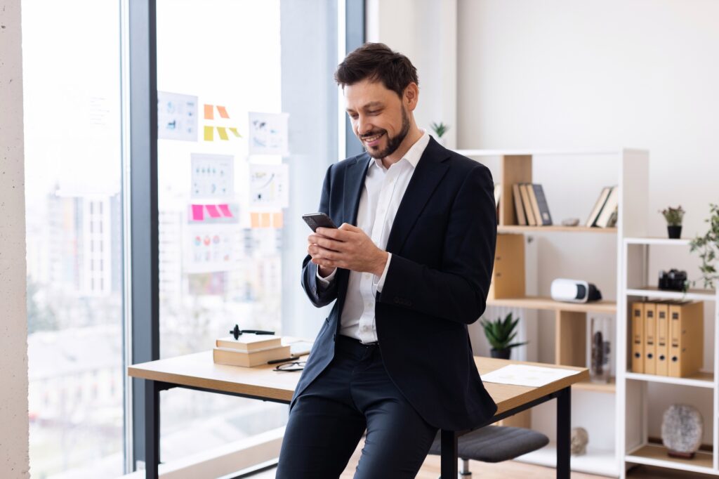 Business professional using smartphone in office environment with city views